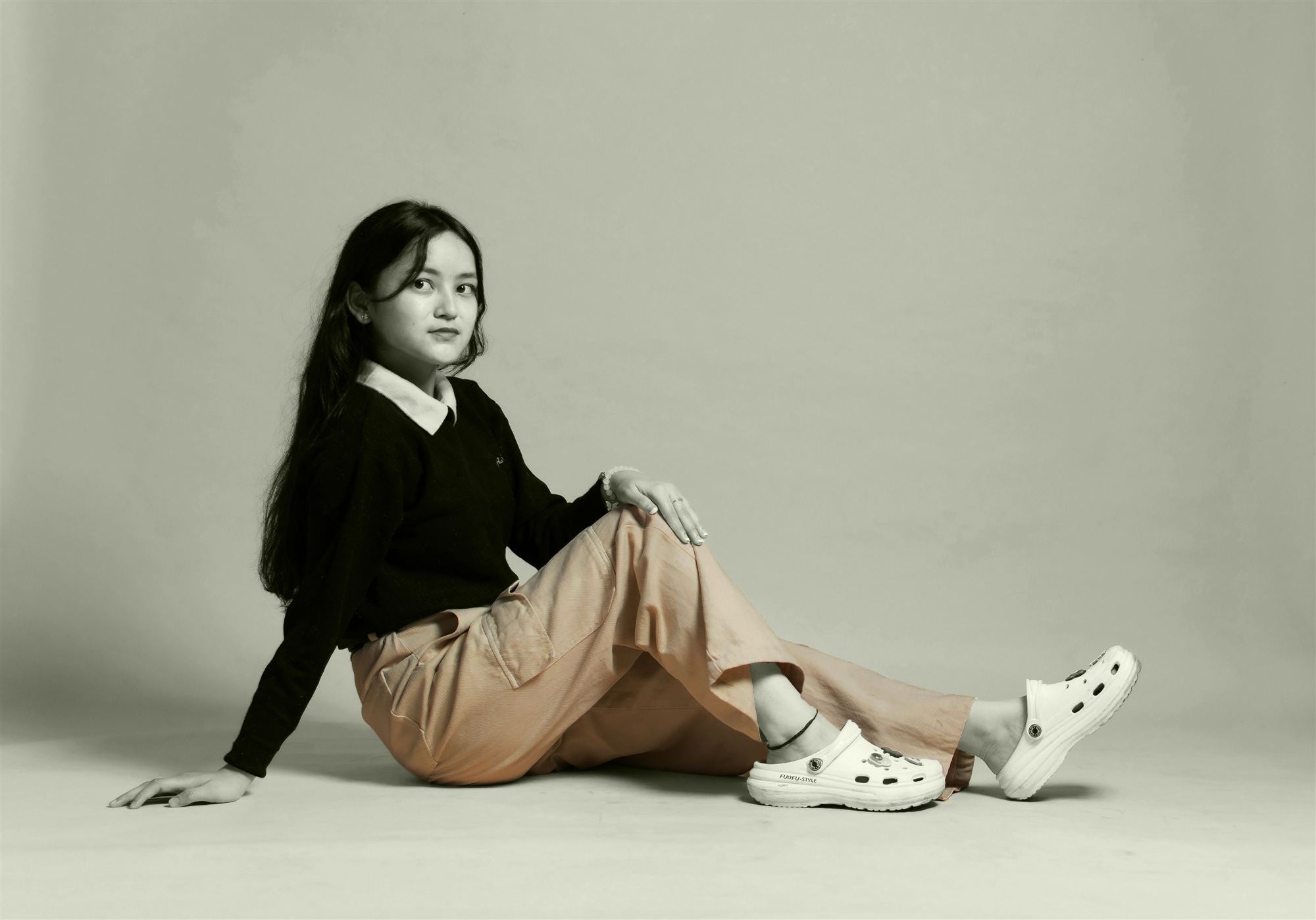 A woman seated on the studio floor in wide-leg petite trousers