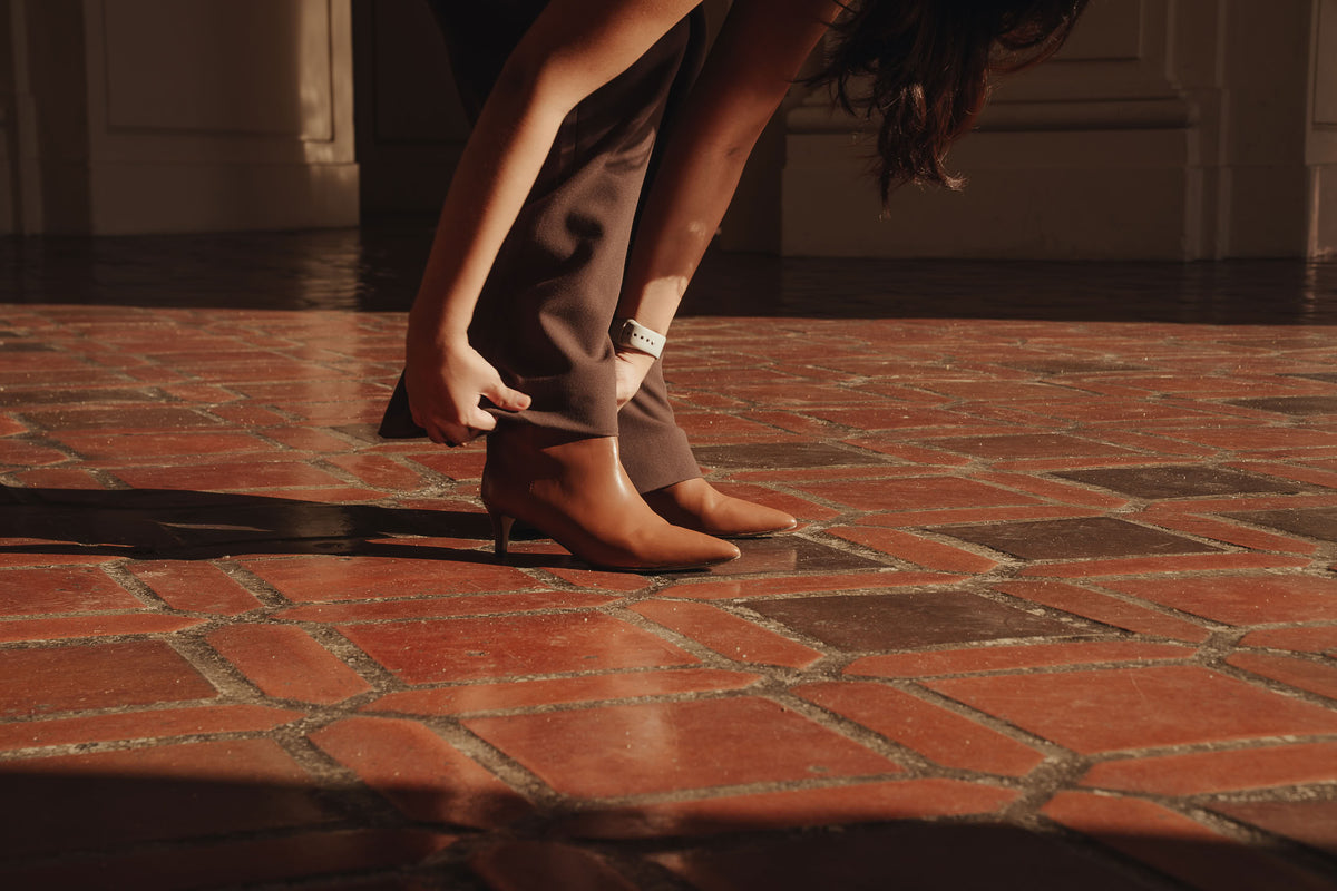 Petite dress pants in Espresso, a deep warm brown, bending to adjust her heels at Pasadena City Hall, The Petite Standard