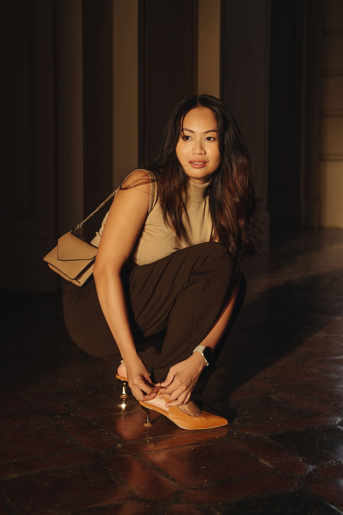 Petite dress pants in Espresso, a deep warm brown, bending to adjust her heels at Pasadena City Hall, The Petite Standard