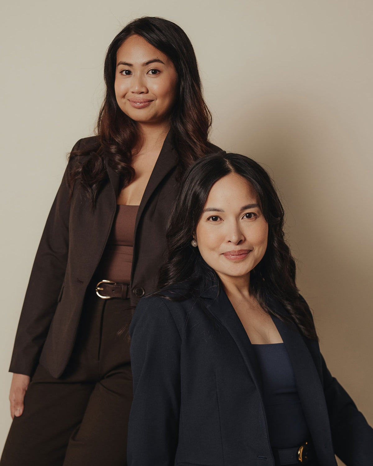 Petite dress pants in Espresso brown and Midnight navy blue, worn by the two founders in a studio portrait