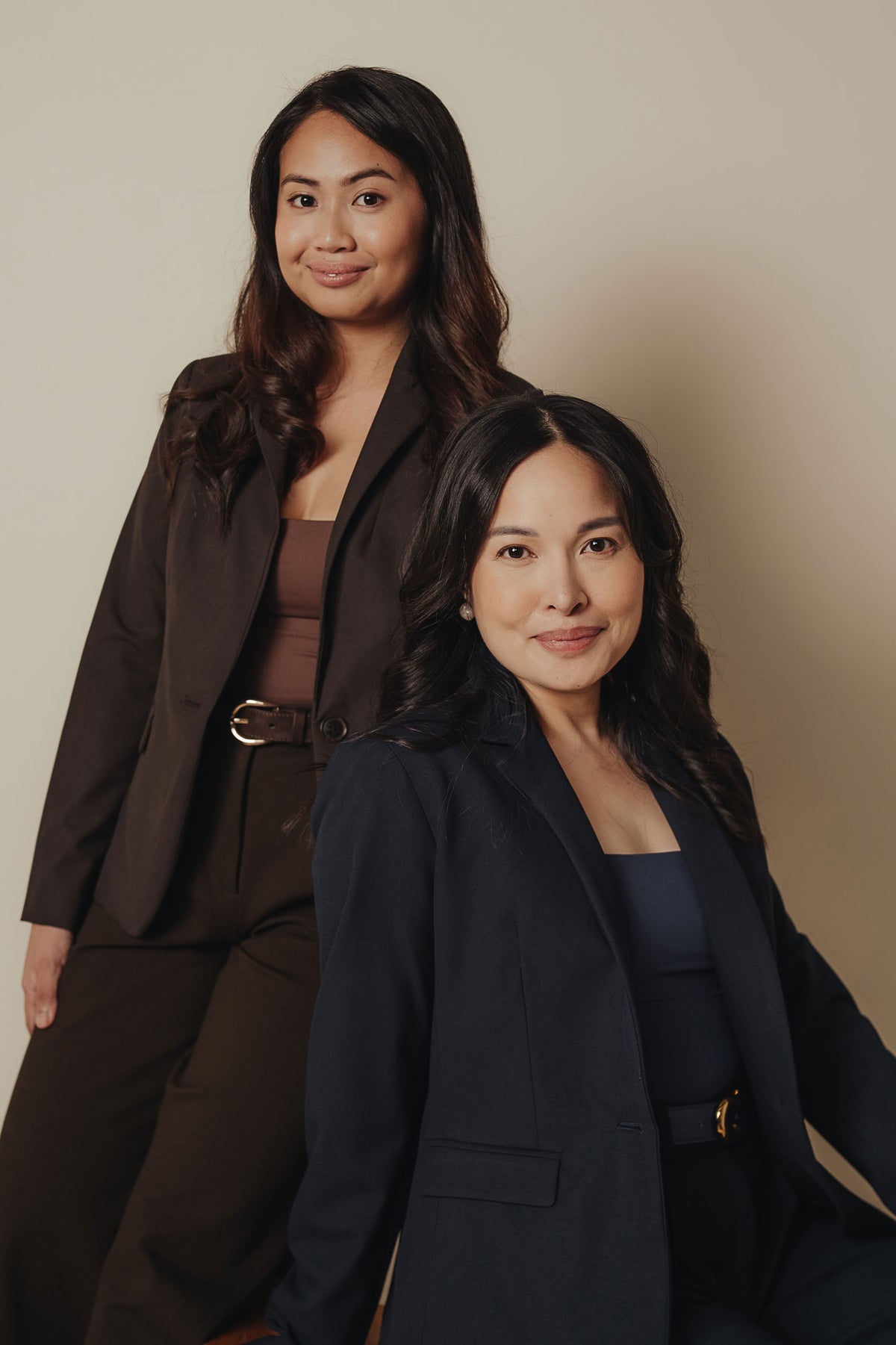 Petite dress pants in Espresso brown and Midnight navy blue, worn by the two founders in the studio with blazers