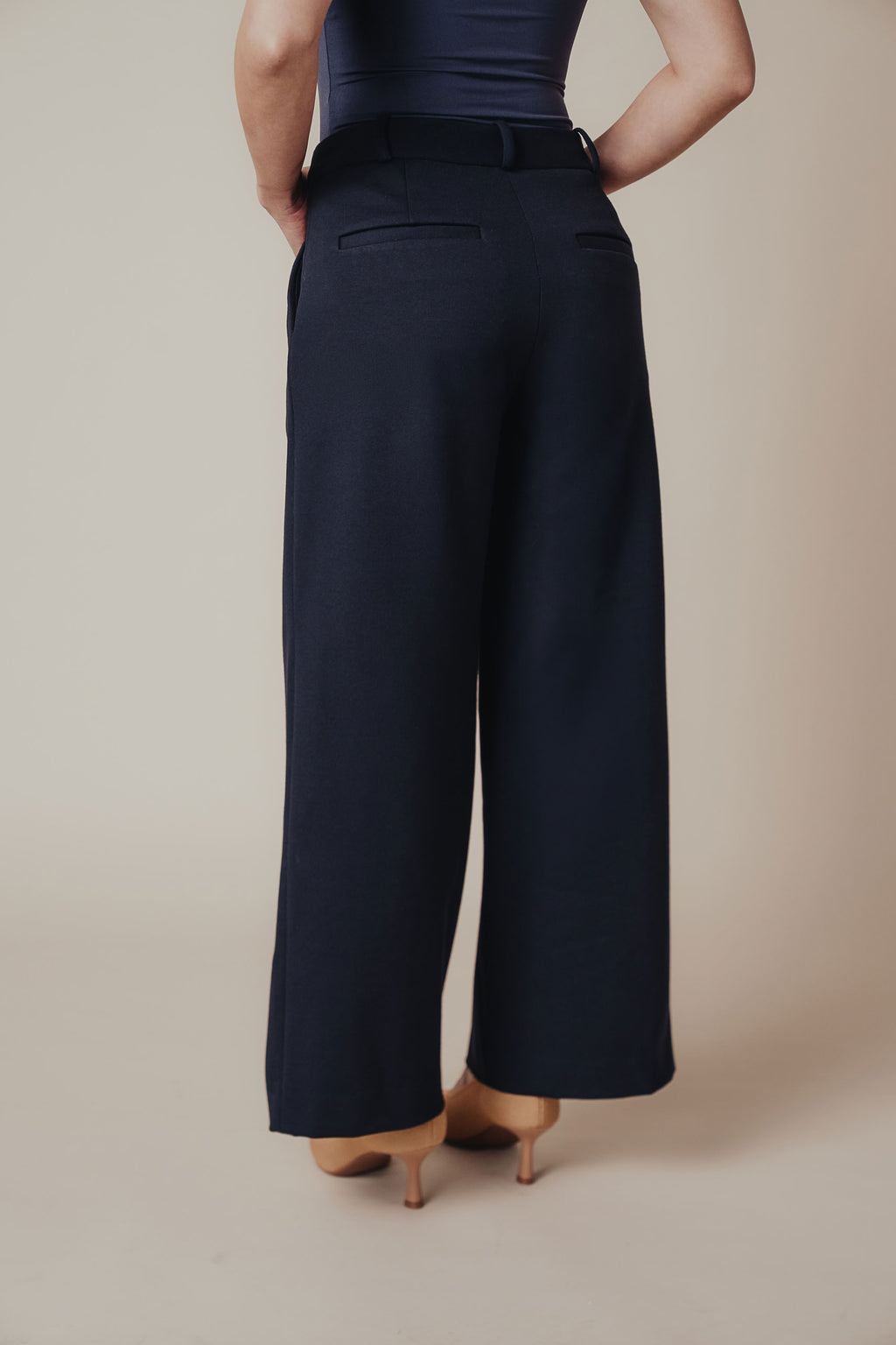 Petite dress pants in Midnight, a deep navy blue, back view showing the back pockets and clean drape, The Petite Standard