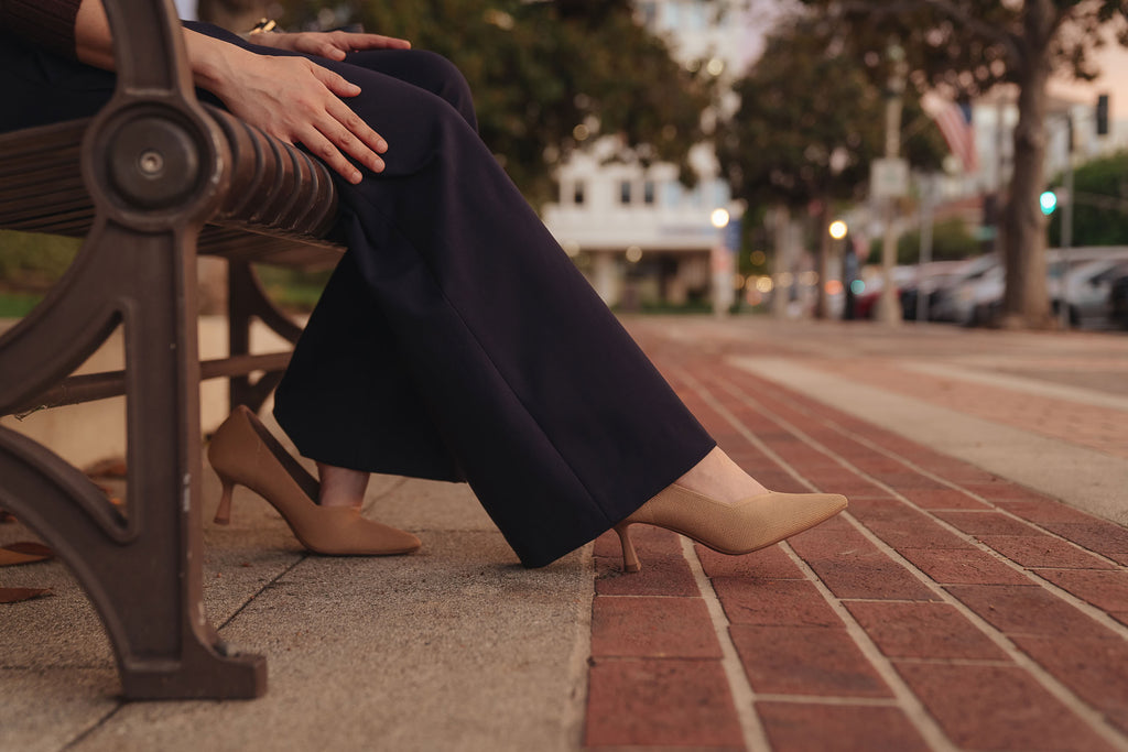 Petite dress pants in Midnight, a deep navy blue, seated outdoors, showing how the pants sit and drape, The Petite Standard