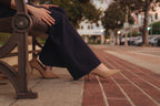 Petite dress pants in Midnight, a deep navy blue, seated outdoors, showing how the pants sit and drape, The Petite Standard