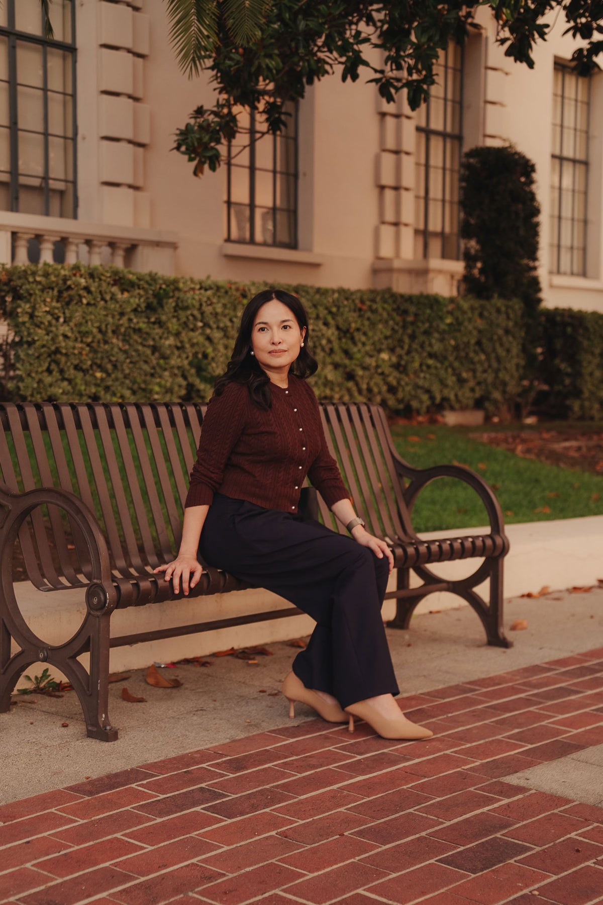 Petite dress pants in Midnight, a deep navy blue, seated outdoors, showing how the pants sit and drape, The Petite Standard