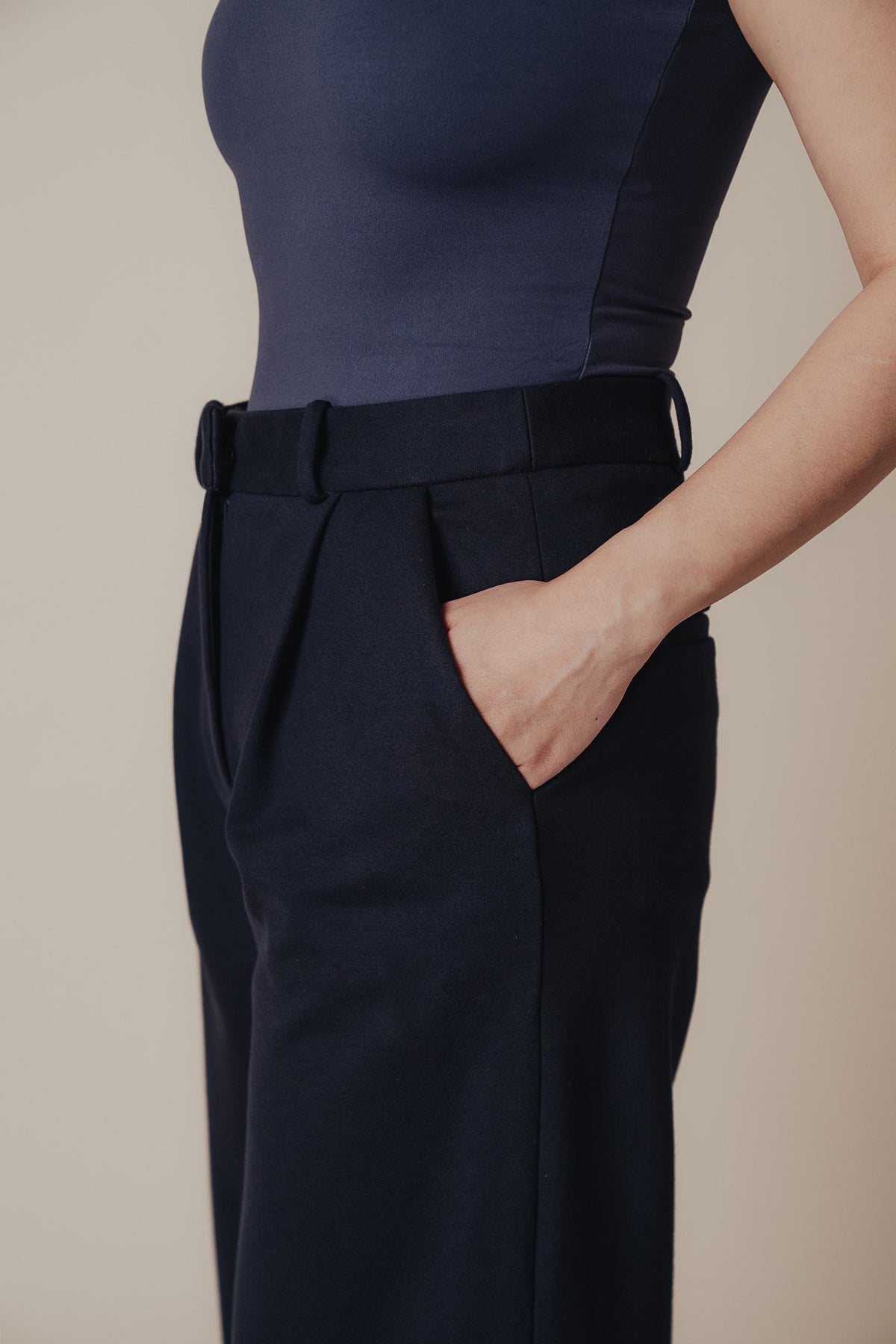 Petite dress pants in Midnight, a deep navy blue, close-up of the waistband, front pleat and side pocket